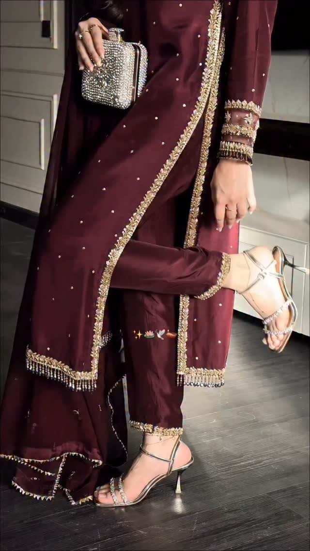 Person wearing a maroon embroidered ethnic outfit with silver heels and a sequined clutch.