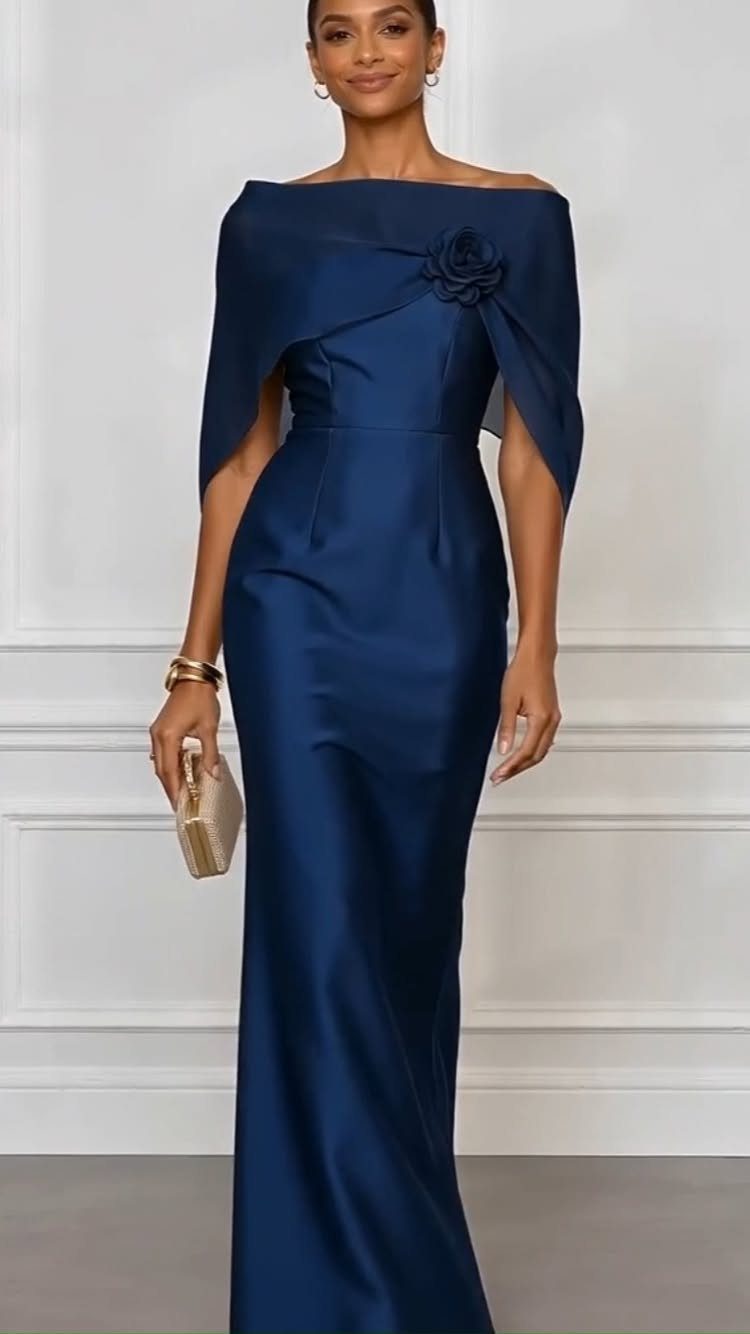Woman wearing a long navy blue satin off-the-shoulder evening gown with a rose detail.