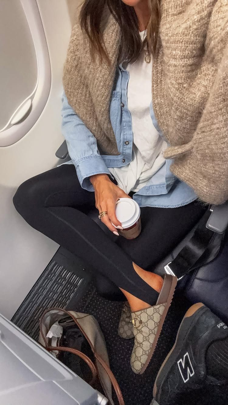 Person wearing a light blue denim button-down shirt and beige cardigan while sitting on an airplane.