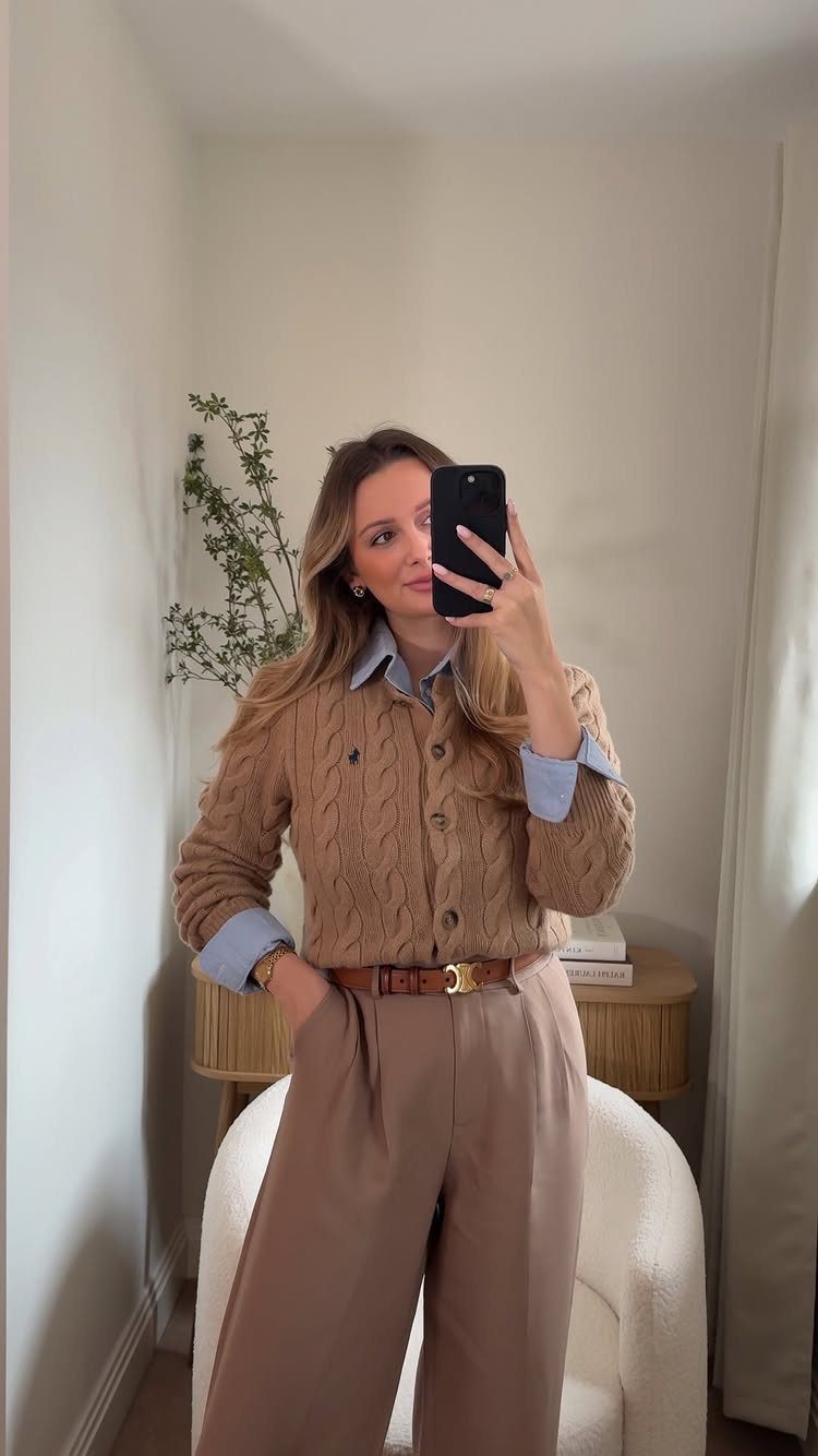 Woman in a mirror selfie wearing a tan cardigan, blue shirt, and tan trousers.