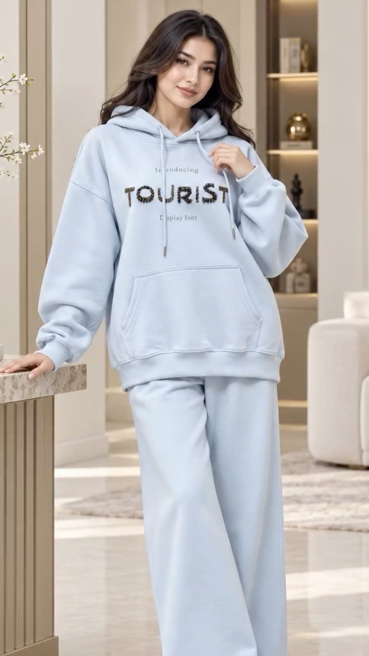 Woman wearing a light blue matching loungewear set with a tourist graphic hoodie and wide-leg pants.
