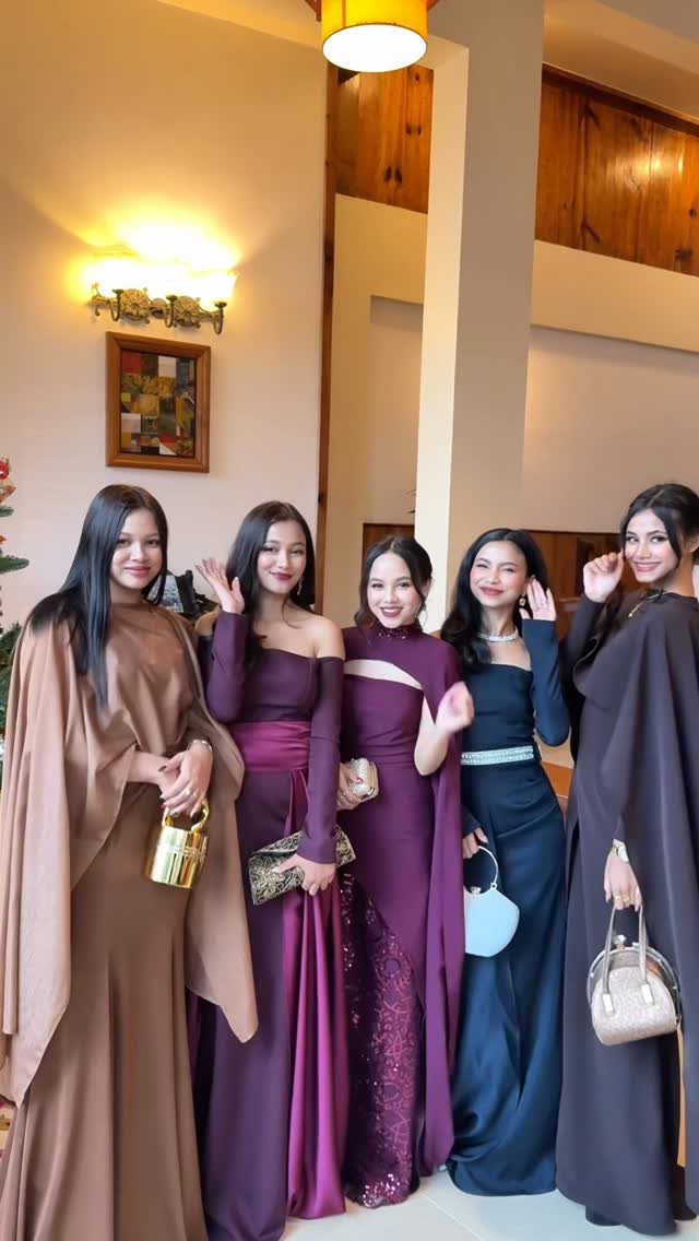 Five women posing in elegant, long formal gowns in various dark colors.