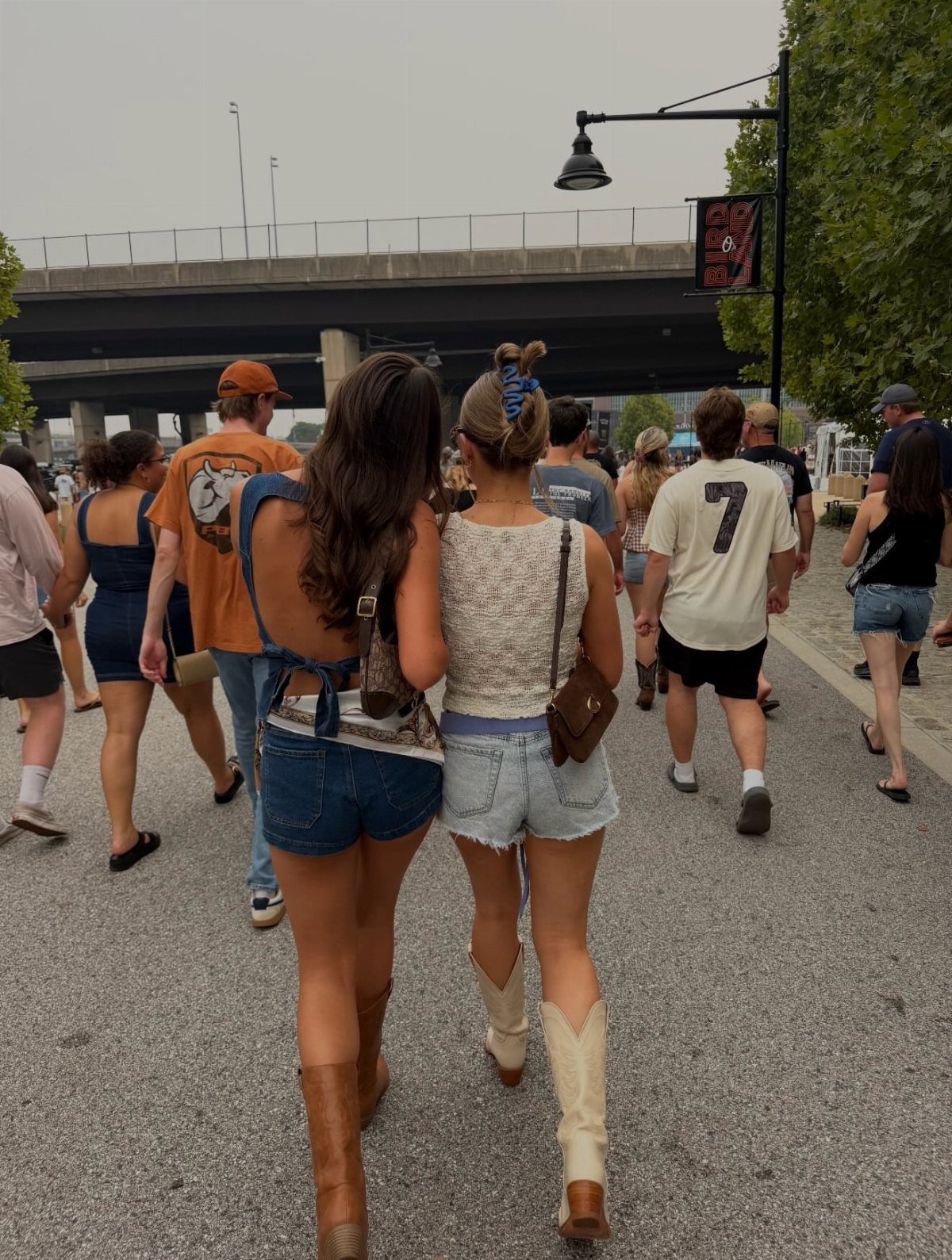 Two women walking down a street wearing denim shorts and cowboy boots.