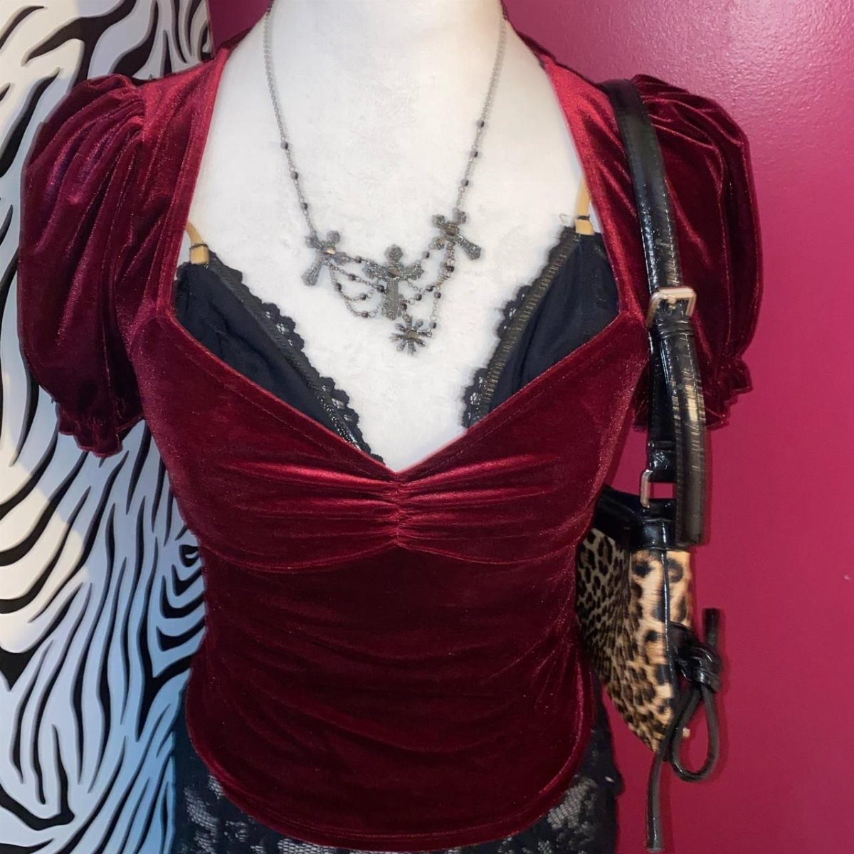 Burgundy velvet puffed sleeve top on a mannequin with a silver necklace and leopard print bag.