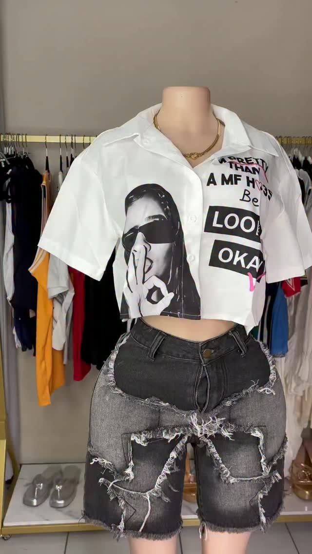 Mannequin wearing a white graphic cropped shirt and distressed grey denim shorts.