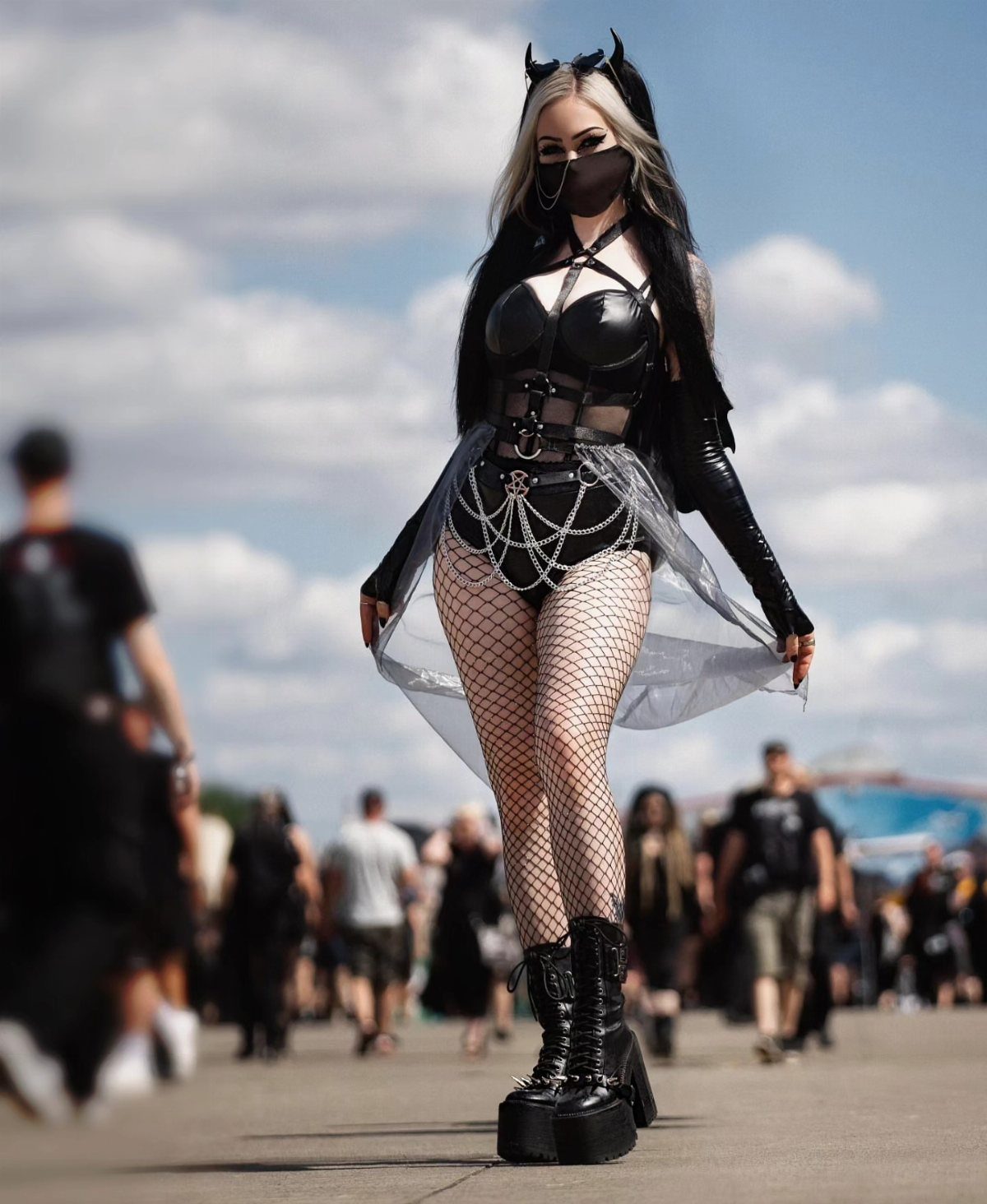 Woman wearing a black corset, fishnet tights, and chunky platform boots standing outdoors.