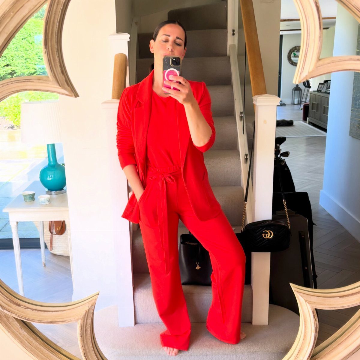 Woman in a vibrant red blazer and wide-leg trousers posing for a mirror selfie.