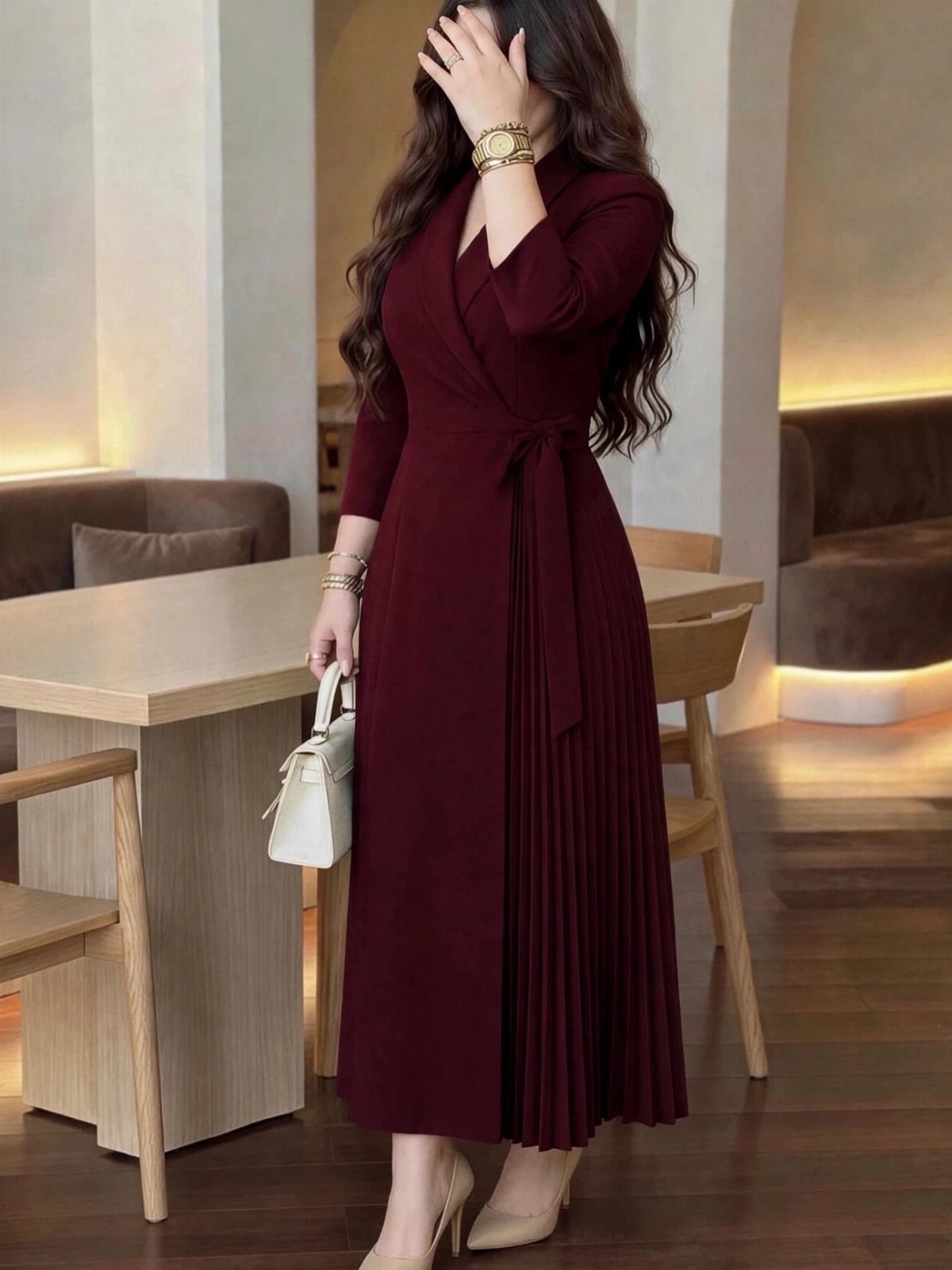 Woman wearing a burgundy long-sleeved wrap midi dress with a pleated skirt and beige heels.