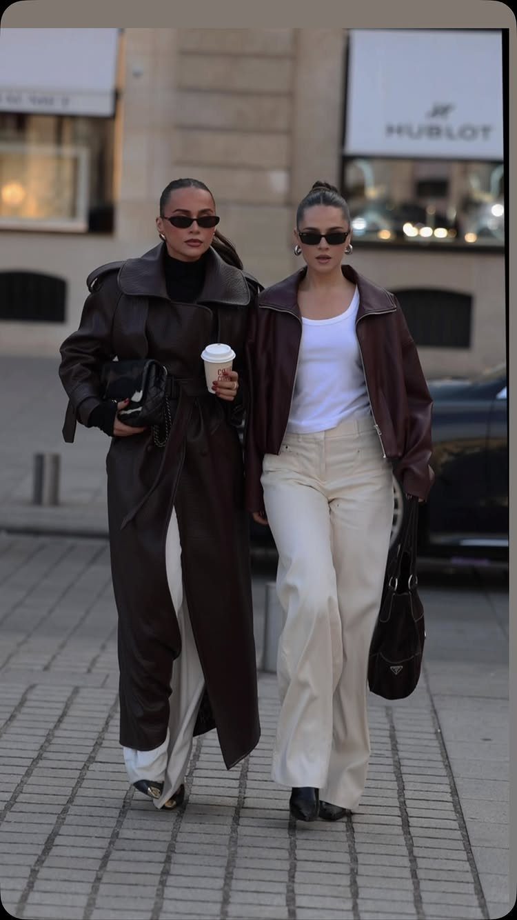 Two women walking down a city street wearing stylish leather jackets and trousers.