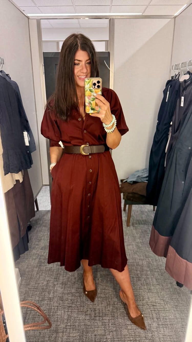 Woman in a reddish-brown button-down midi dress with a brown belt posing in a fitting room.