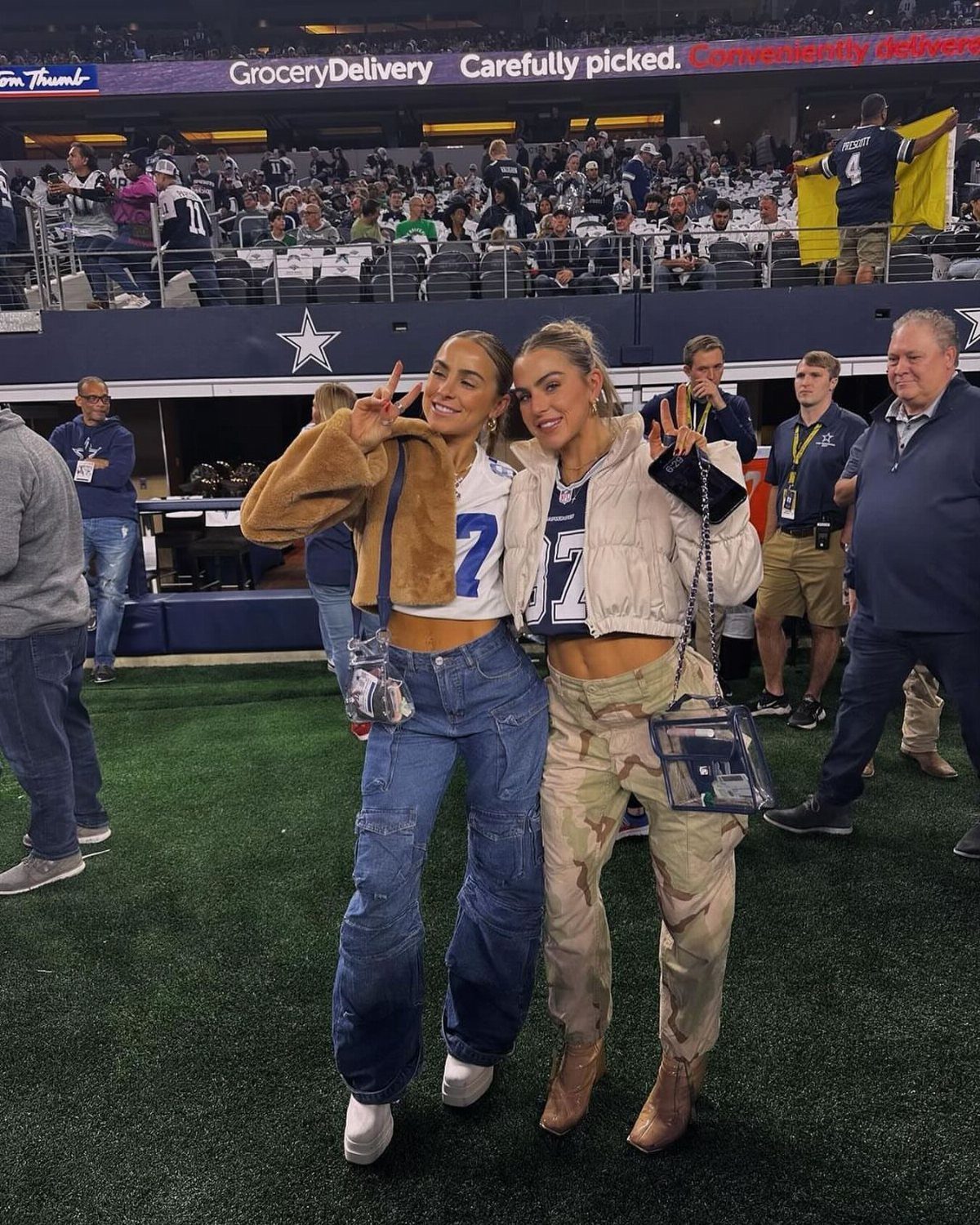 Two women posing on a football field wearing jerseys and cargo pants.