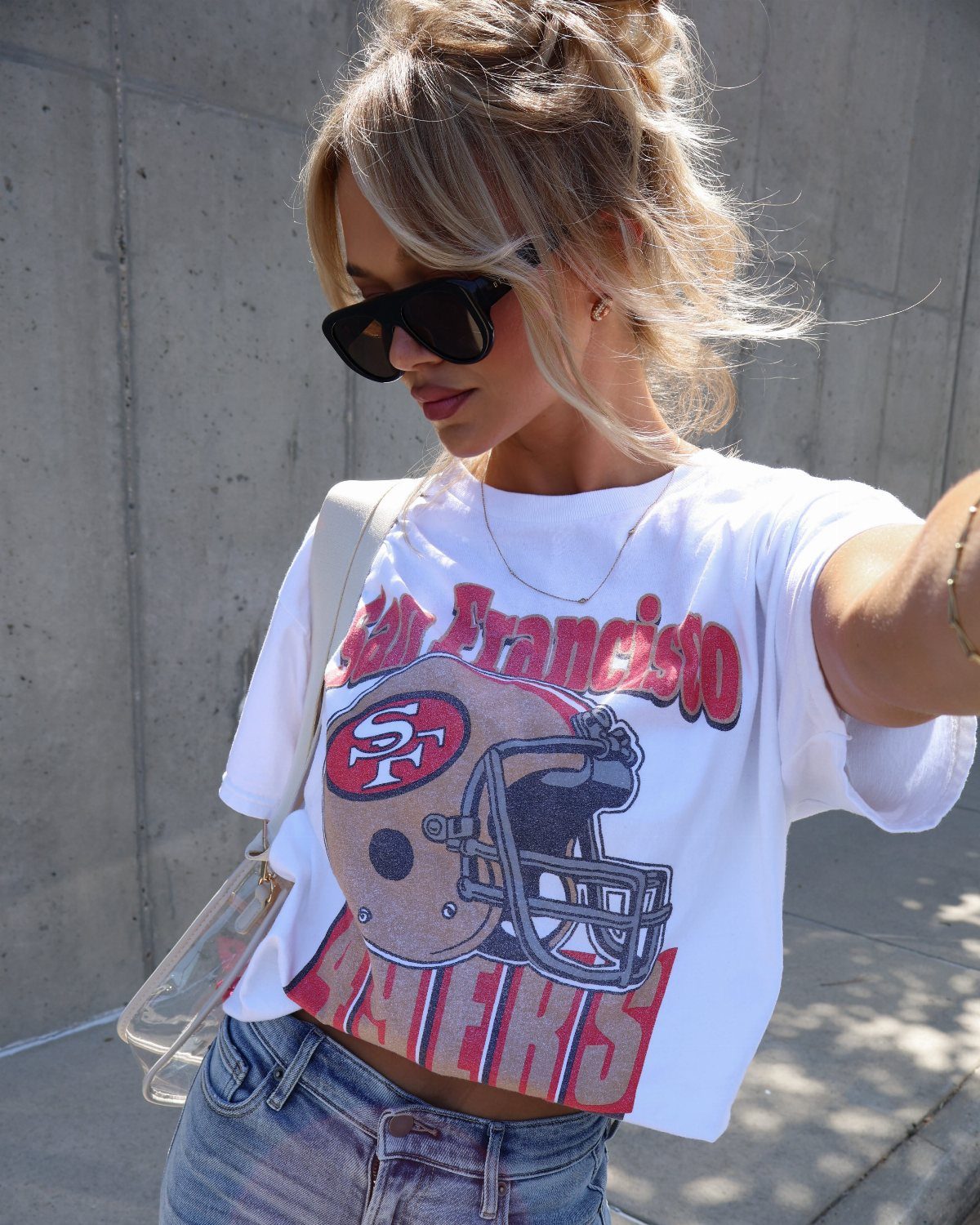 Woman wearing a white vintage San Francisco 49ers graphic t-shirt and blue denim jeans.