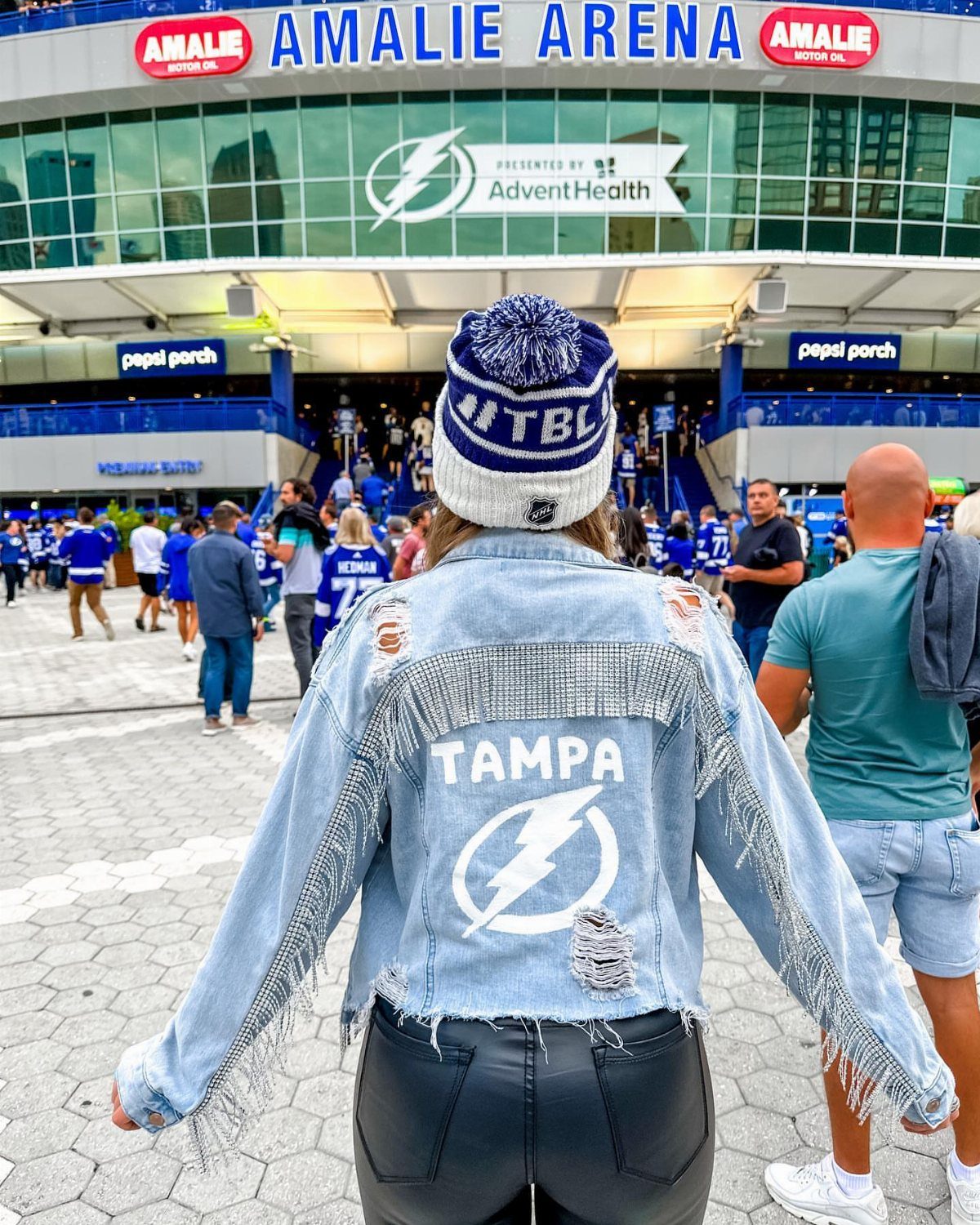 Person wearing a custom Tampa denim jacket and beanie standing outside Amalie Arena.