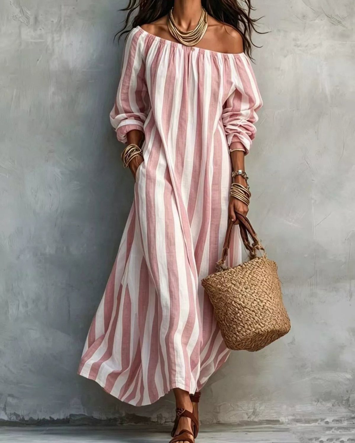 Woman in a pink and white striped off-the-shoulder maxi dress carrying a straw bag.
