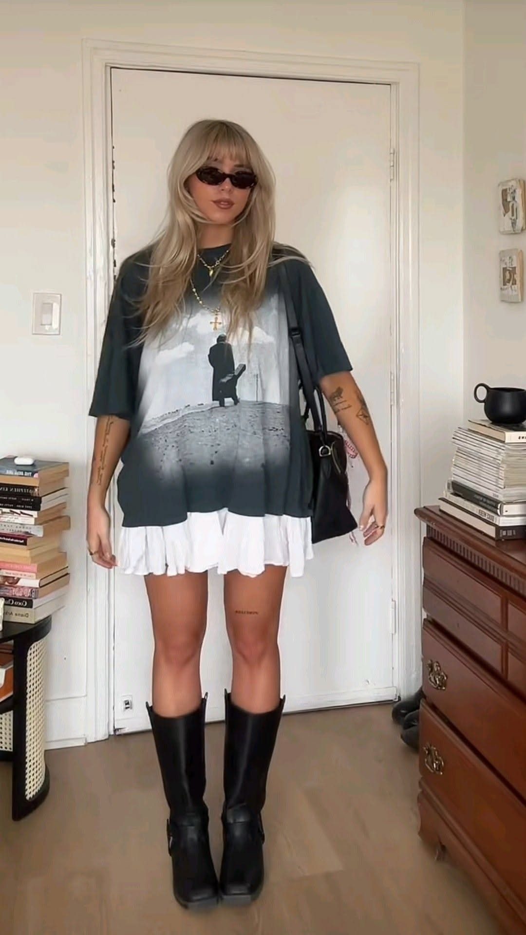 Woman wearing an oversized graphic t-shirt, white ruffled mini skirt, and black boots.