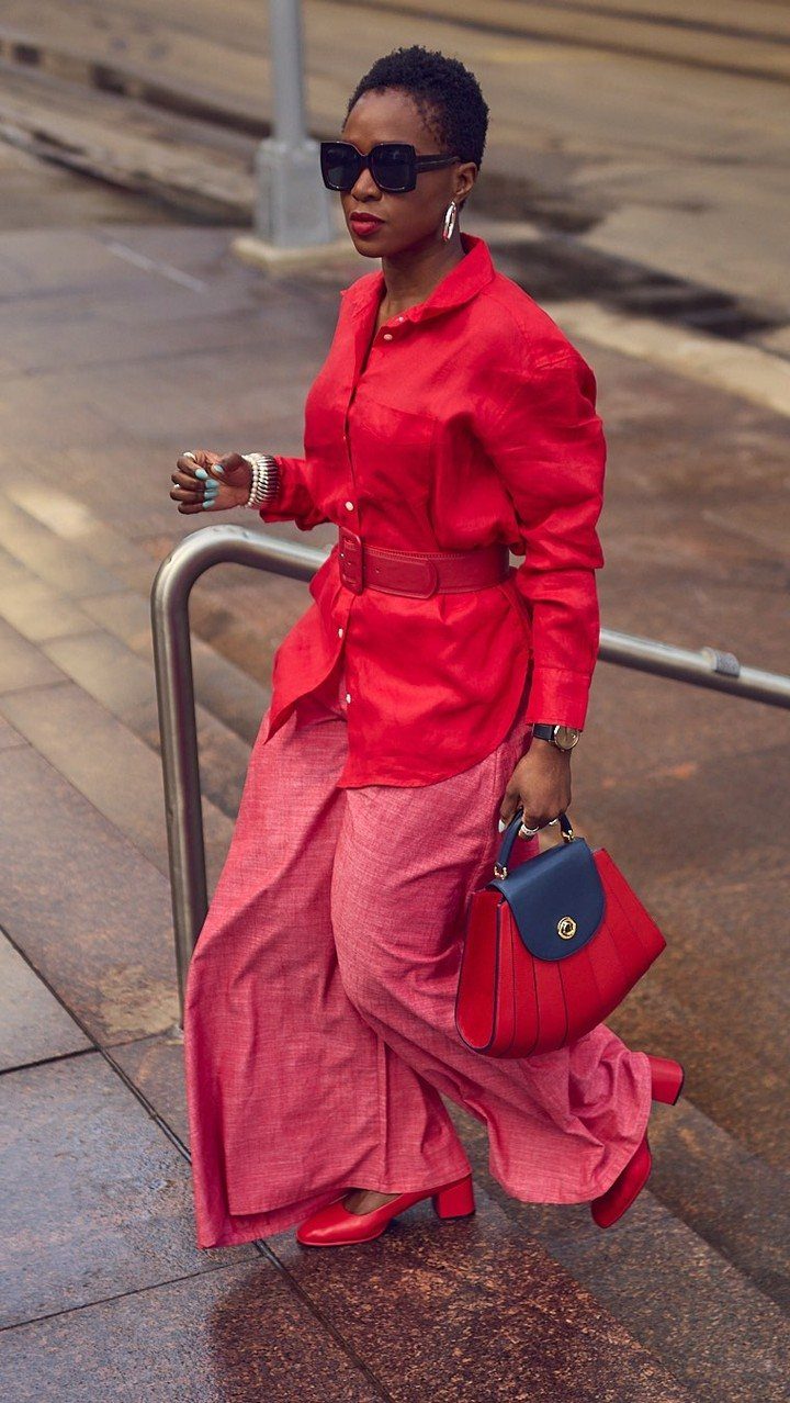 Woman in a vibrant red monochrome outfit walking down outdoor stairs with a red handbag.