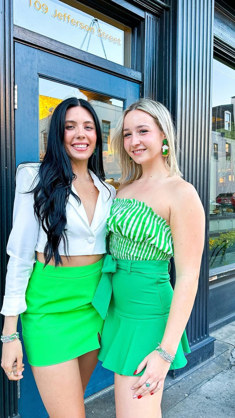 Two women posing in bright green and white outfits suitable for St. Patrick's Day.