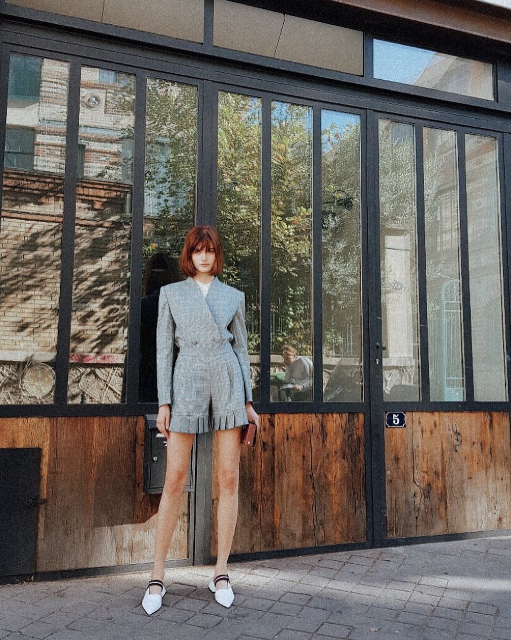 Woman wearing a light blue patterned blazer and matching tailored shorts standing outdoors.