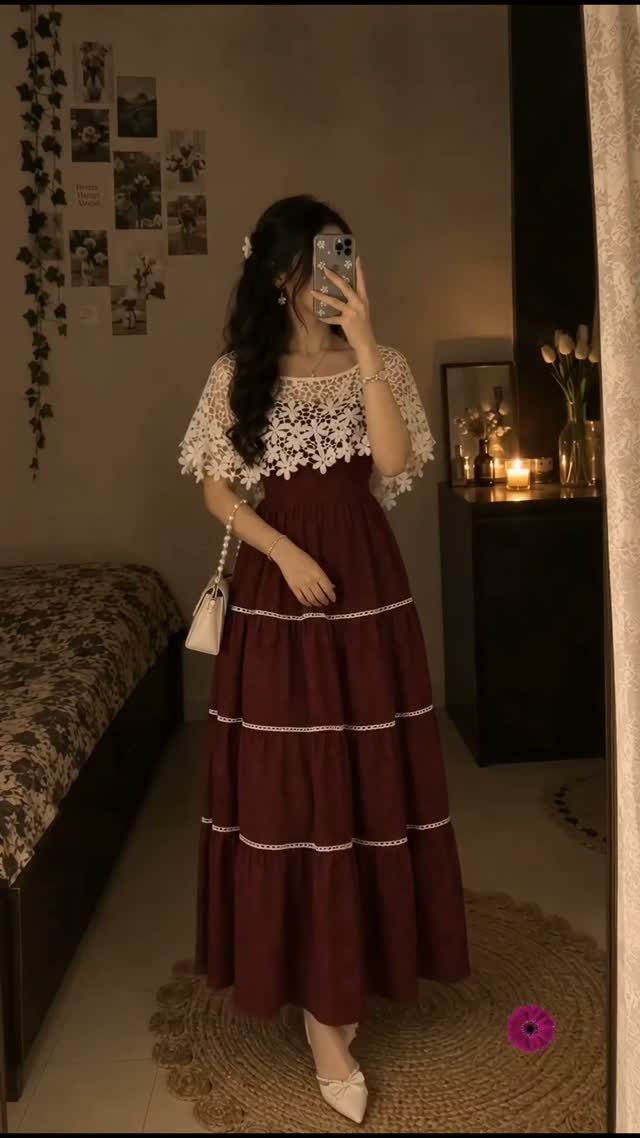 Woman posing in a maroon tiered maxi dress with white lace trim in a bedroom.