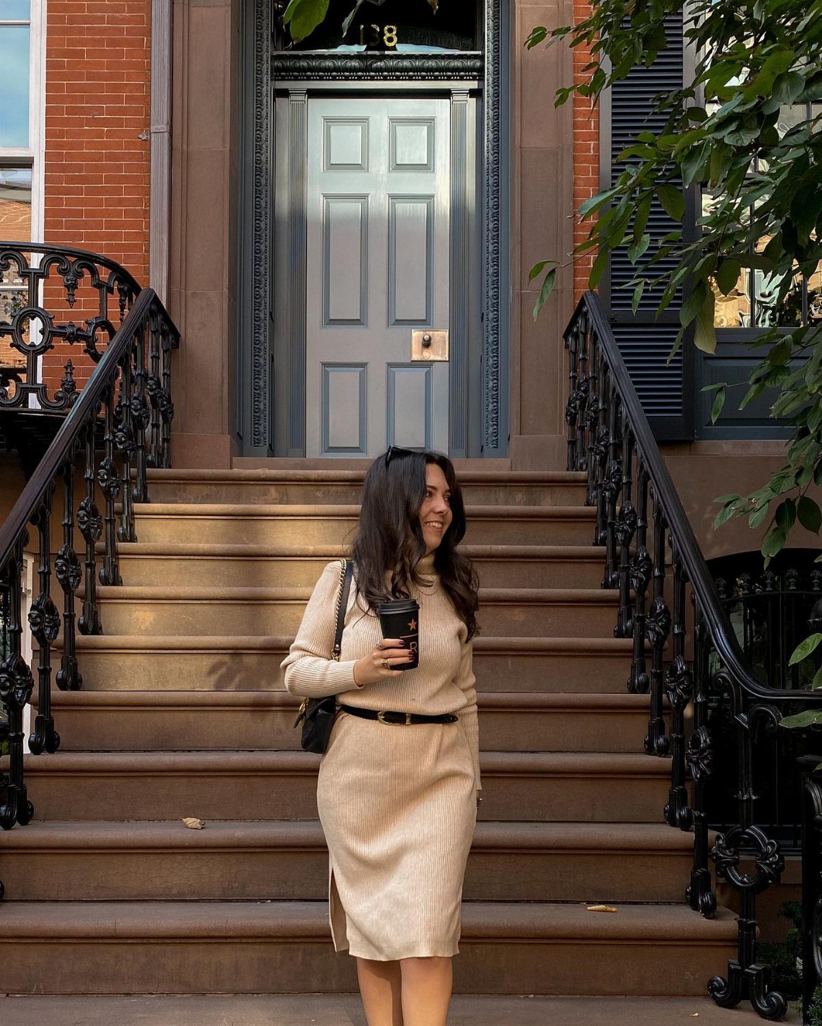 Woman in a beige ribbed midi dress standing on outdoor stone steps.