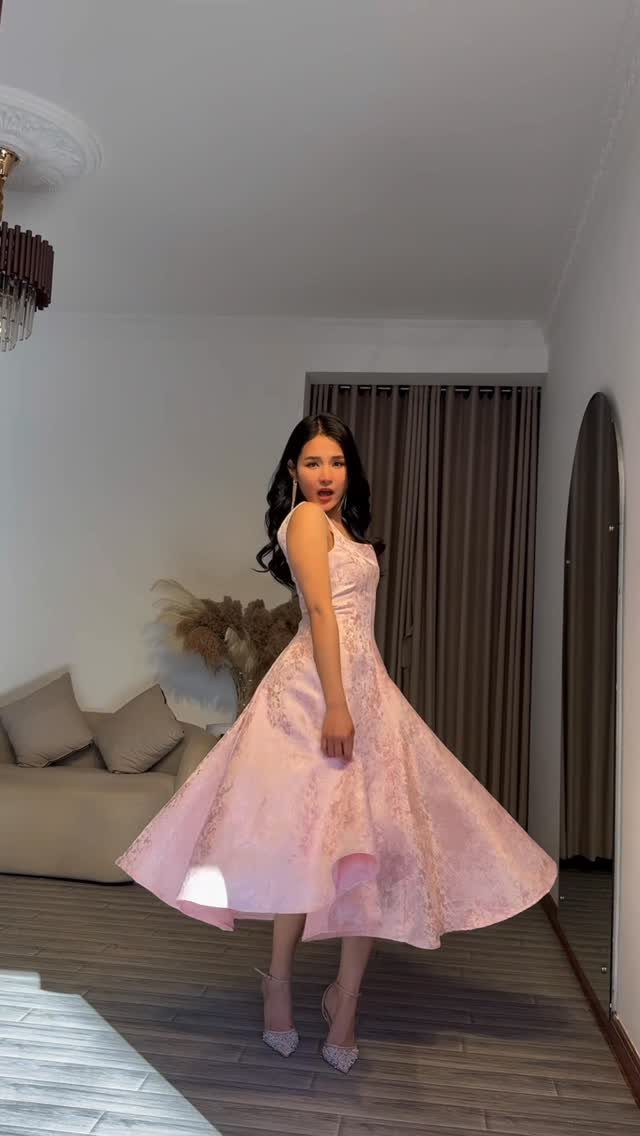 Woman posing in a light pink sleeveless floral A-line dress and heels.