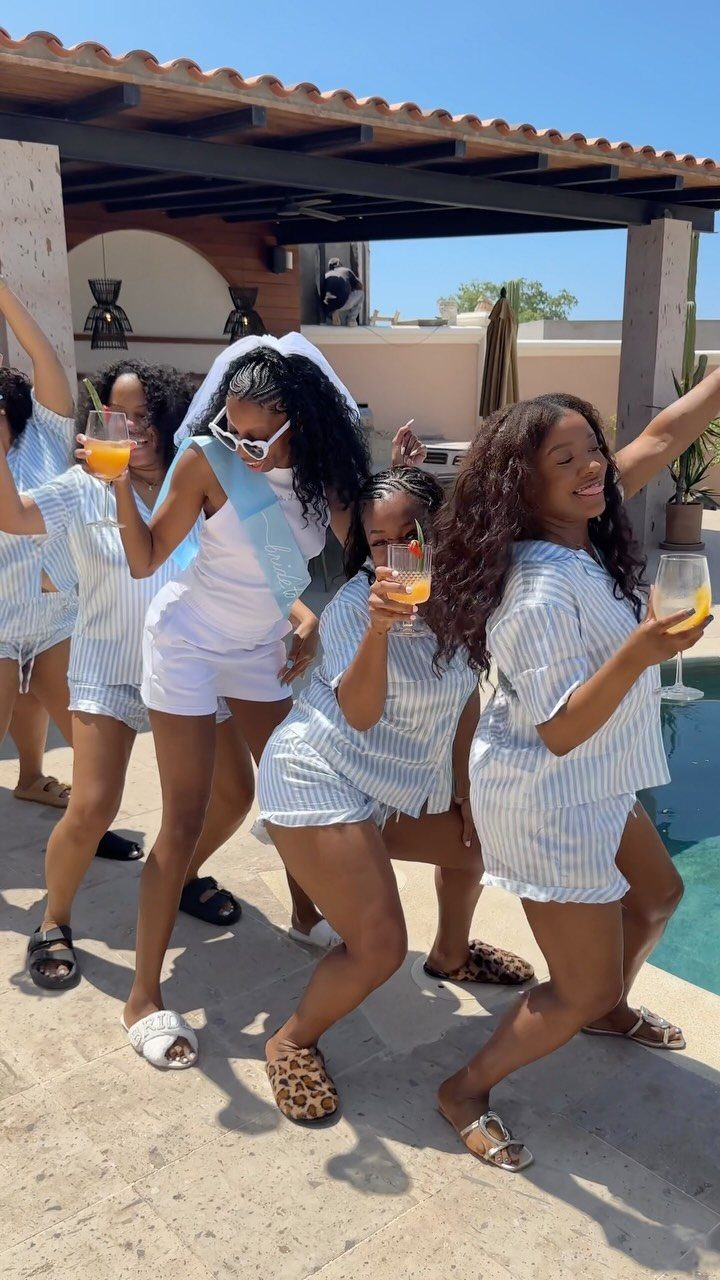 Women in matching striped pajamas posing together outdoors near a swimming pool.