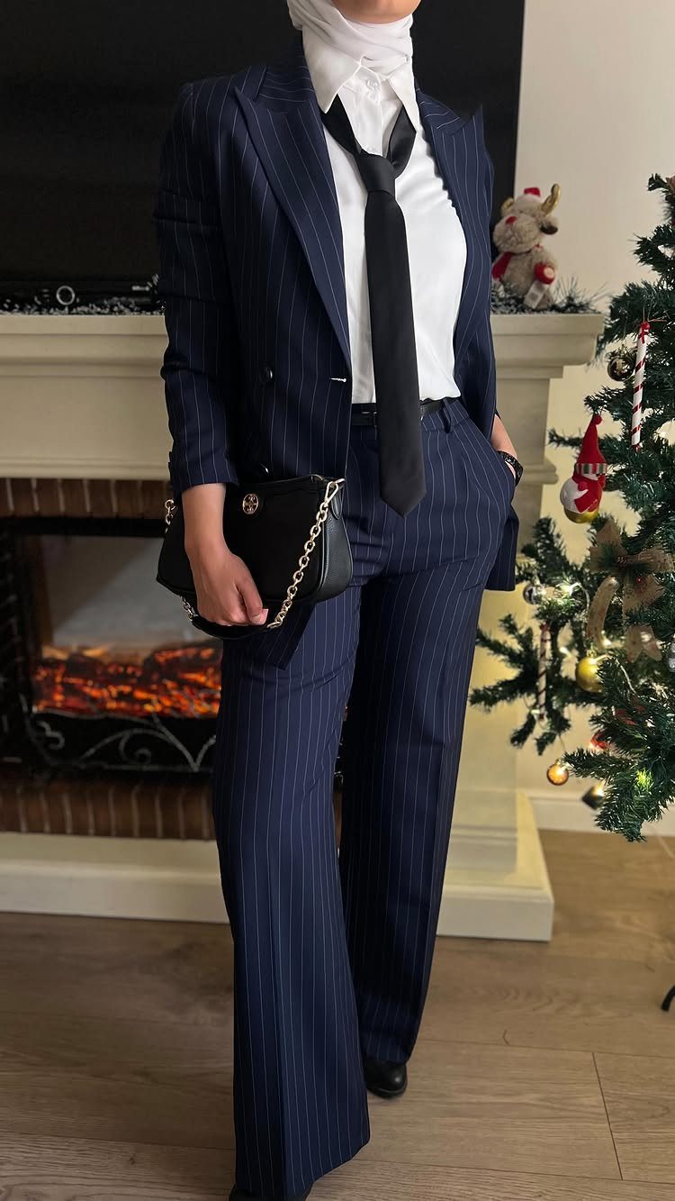 Woman wearing a navy pinstripe suit with a white shirt and black tie.