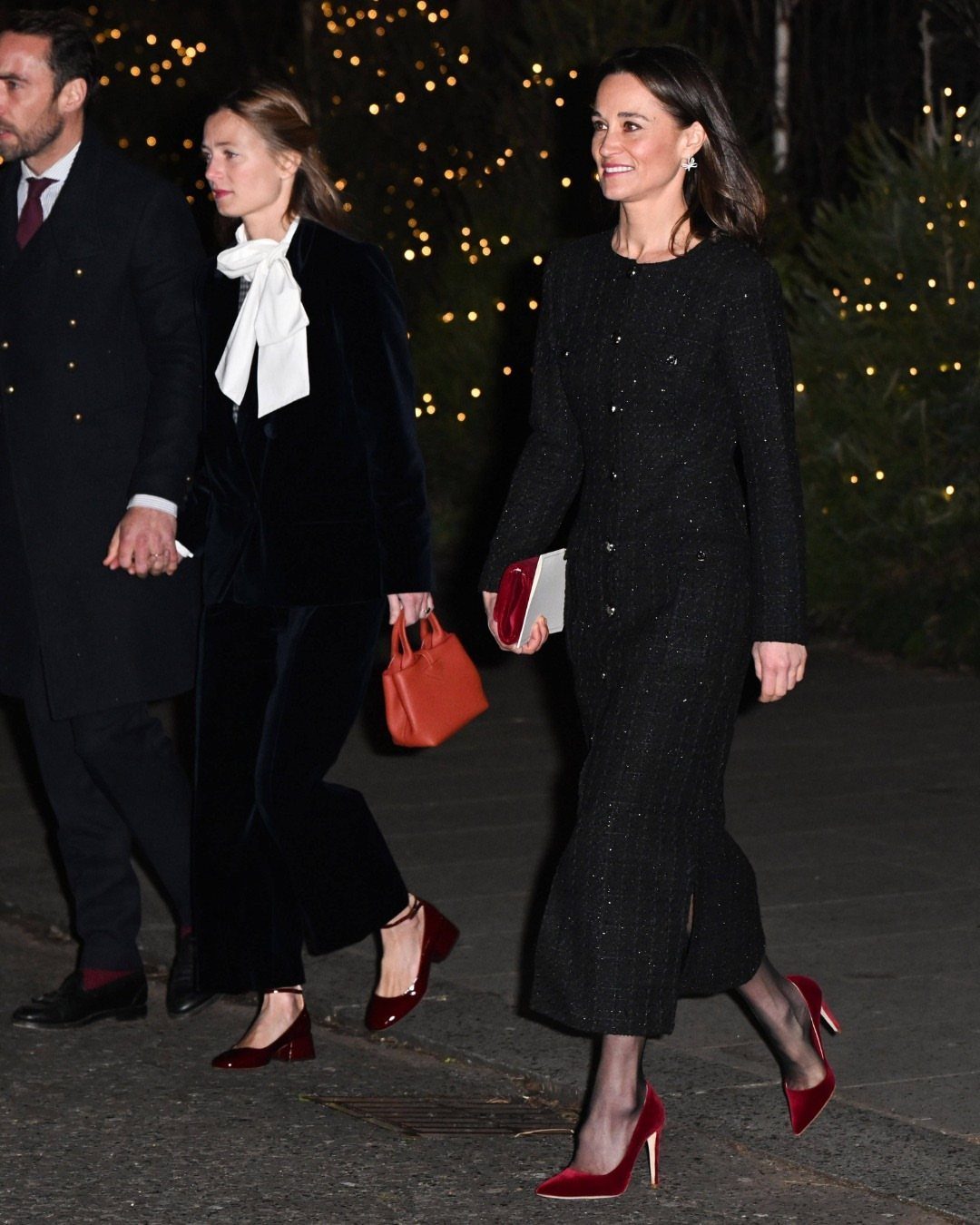 Women walking at night wearing elegant black velvet outfits and red high heels.