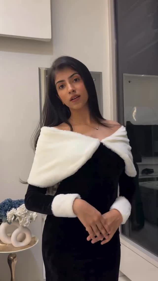 Woman wearing a black velvet dress with white faux fur trim around the neckline and cuffs.