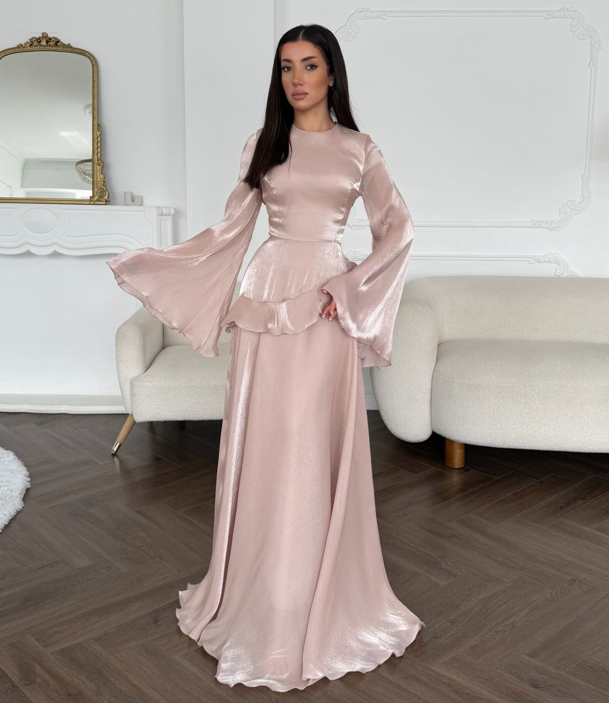 Woman wearing a shimmering pale pink long-sleeved maxi dress with dramatic bell sleeves.