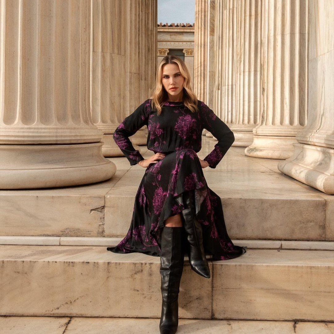 Woman in a black and purple floral long-sleeved dress sitting on marble steps.