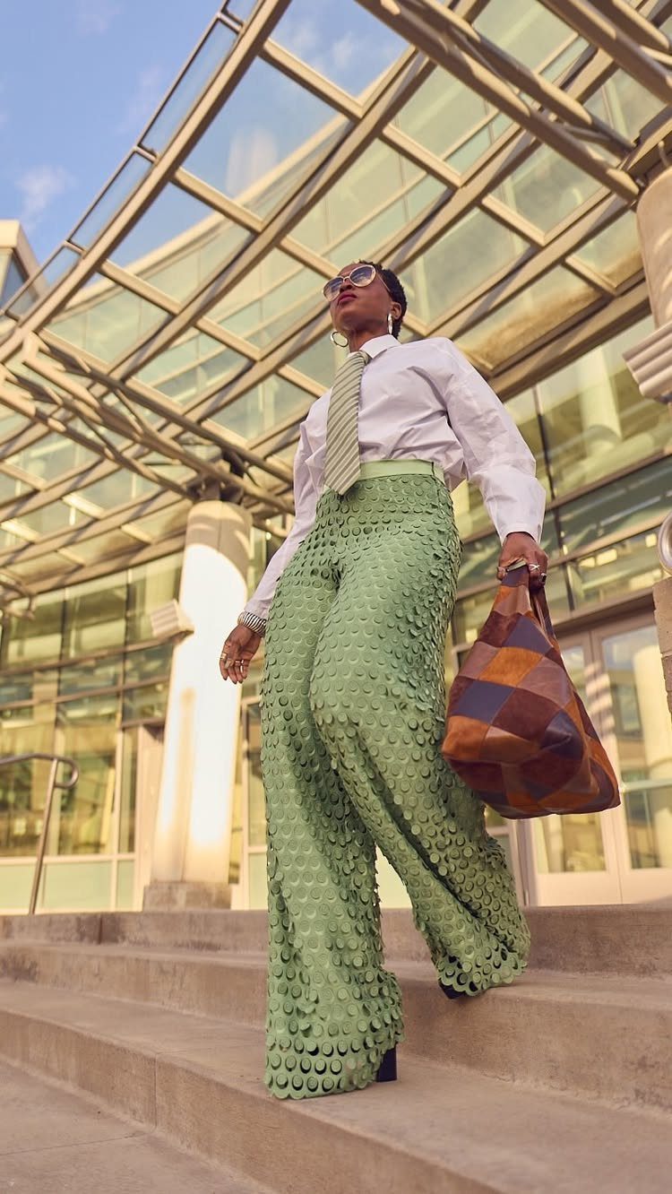 Woman in white shirt and green textured wide-leg pants walking up outdoor stairs.