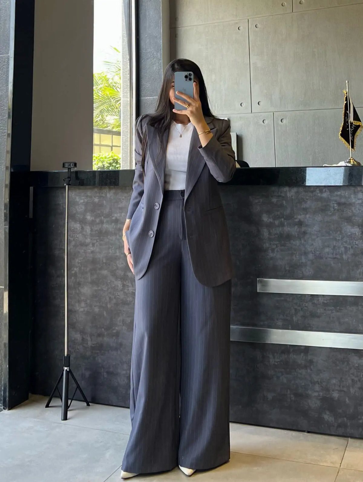 Person posing in a charcoal grey pinstripe blazer and matching wide leg trousers.